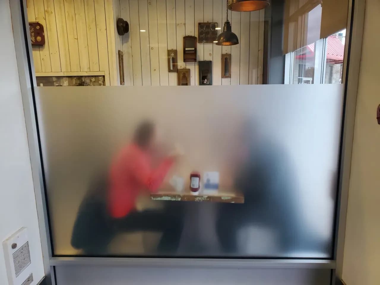 Glass partition with frosted film giving privacy to a dining area